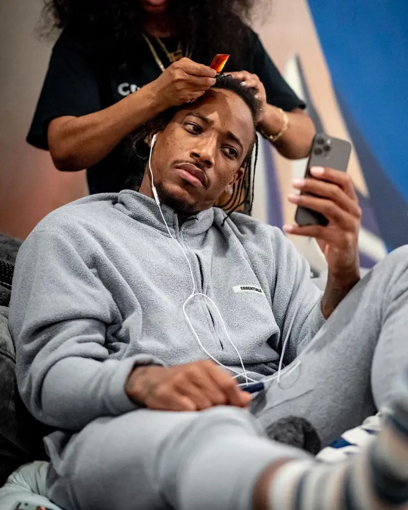 DeMar playing with his handset while having his hair done on April 29